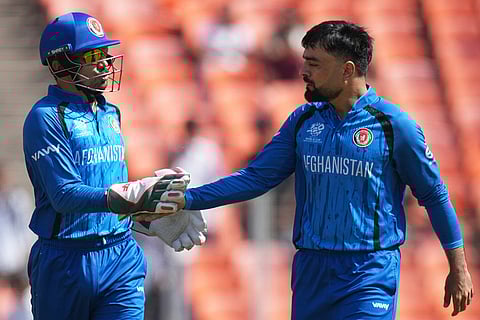 Afghanistan's captain Rashid Khan, right and Mohammad Nabi celebrates the dismissal of South Africa's Quinton de Kock during the T20 World Cup cricket match between Afghanistan and South Africa in Ahmedabad.