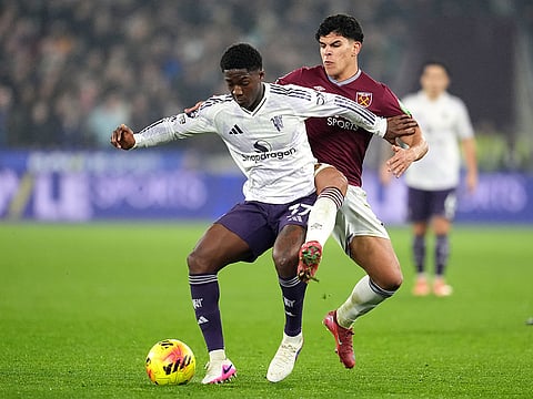Manchester United's Kobbie Mainoo, left, and West Ham United's Mateus Fernandes battle for the ball during a Premier League soccer match in London.