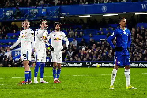 Chelsea's Joao Pedro stands in the goalkeeper's eyeline as Leeds players form a defensive wall, during their English Premier League soccer match in London.
