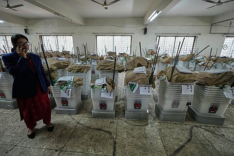 An official stands near ballot boxes and voting papers before its distribution to various polling centers ahead of Thursday's national parliamentary election, in Dhaka, Bangladesh, Wednesday, Feb. 11, 2026. 