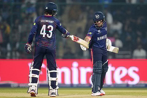 Namibia's Louren Steenkamp, left, extends his bat to batting partner Nicol Loftie-Eaton who meets it with his glove gloved hand during the T20 World Cup cricket match between India and Namibia in New Delhi.