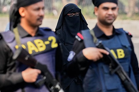 A Bangladeshi woman arrives to cast her vote as security personnel stand guard outside a polling station during national parliamentary election in Dhaka, Bangladesh, Thursday, Feb. 12, 2026. 