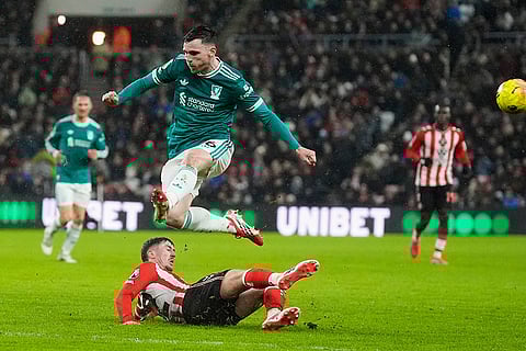 Sunderland's Trai Hume, bottom, slides in the tackle of Liverpool's Andrew Robertson during the English Premier League soccer match, in Sunderland, England.