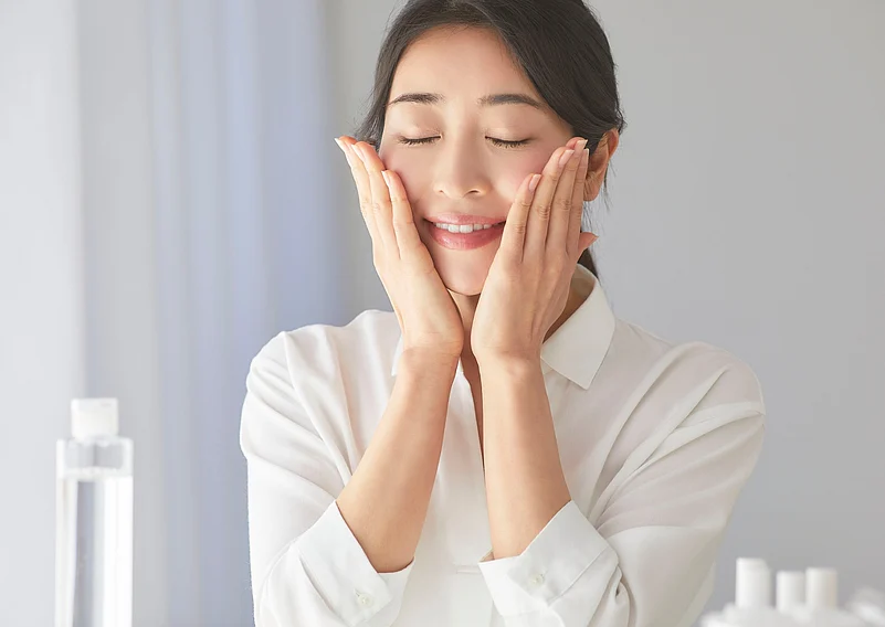 A women smiling and touching her face, illustrating the benefits of antioxidants for skin.