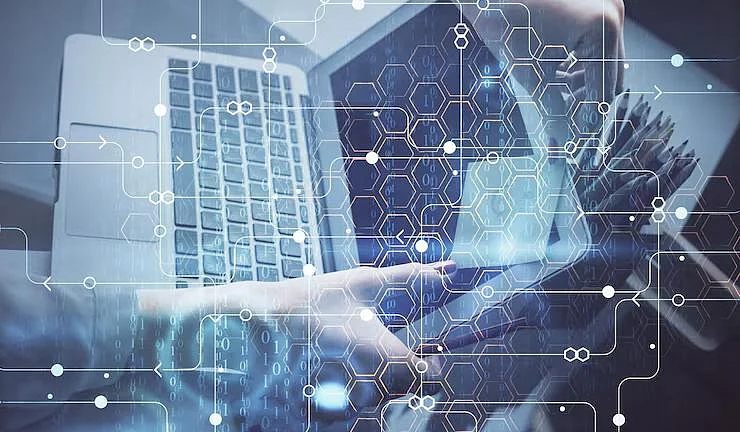 A person using a laptop with digital network and geometric data overlays