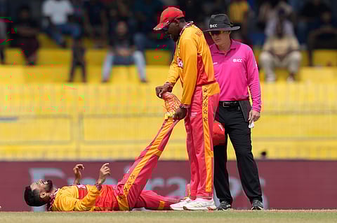 Zimbabwe's captain Sikandar Raza, left, lies on ground after a muscle cramp in his leg during the T20 World Cup cricket match between Australia and Zimbabwe in Colombo.