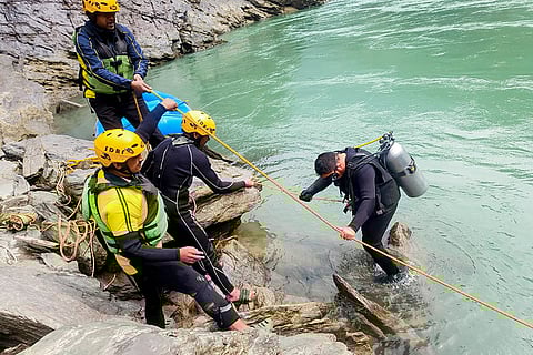SDRF personnel conduct a search operation after a pickup vehicle reportedly fell into a river, in Tehri Garhwal district, Uttarakhand.