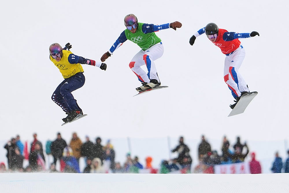 United States' Nathan Pare (13), France's Jonas Chollet (4) and France's Loan Bozzolo (5) compete during the men's snowboard cross finals at the 2026 Winter Olympics, in Livigno, Italy. - | Photo: AP/Lindsey Wasson