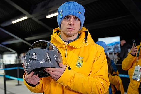 Ukrainian skeleton athlete Vladyslav Heraskevych holds his crash helmet as he stands in the mixed zone of the sliding center at the 2026 Winter Olympics, in Cortina d'Ampezzo, Italy.