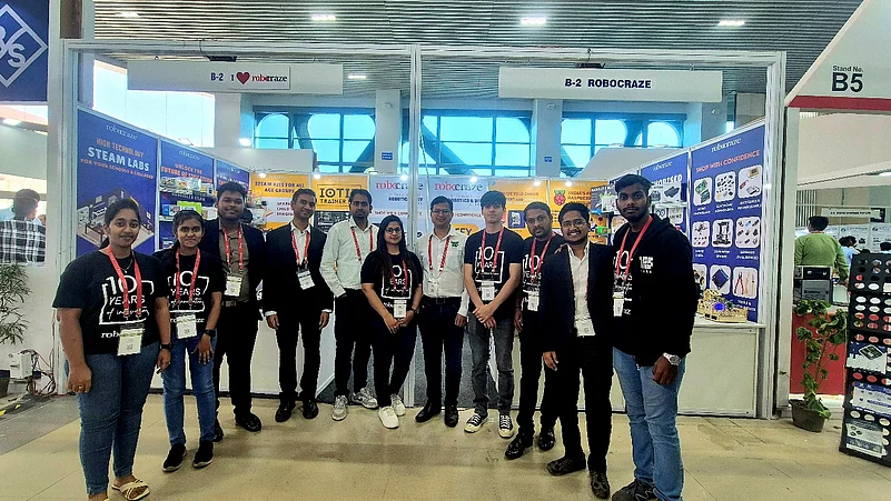A team of ten professionals posing in front of a Robocraze booth at a technology trade show