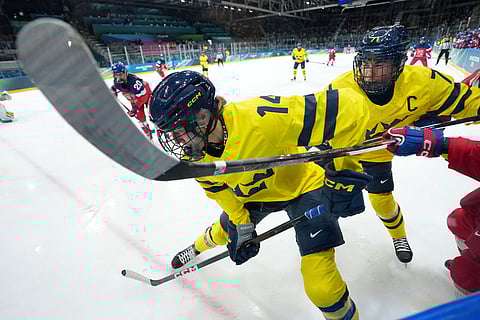 Sweden's Ida Karlsson (14) and Anna Kjellbin (71) try to clear the puck out of the corner during the second period of a women's ice hockey quarterfinal match between Sweden and Czechia at the 2026 Winter Olympics, in Milan, Italy.