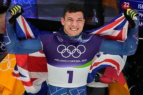 Britain's gold medalist Matt Weston celebrates as he arrives at the finish during a men's skeleton run at the 2026 Winter Olympics, in Cortina d'Ampezzo, Italy.