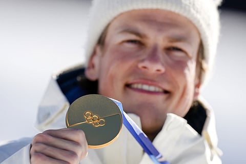 Johannes Hoesflot Klaebo, of Norway, poses after winning the gold medal in the cross country skiing men's 10km interval start free at the 2026 Winter Olympics, in Tesero, Italy.