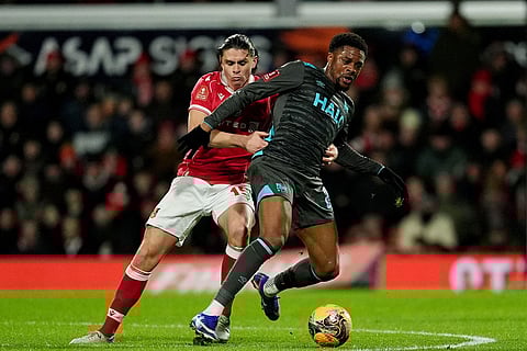 Ipswich Town's Chuba Akpom, right, shields the ball from Wrexham's George Dobson during an English FA Cup fourth round soccer in Wrexham, Wales.