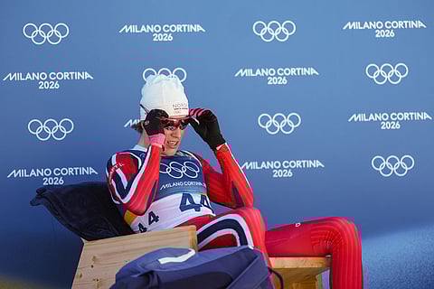Johannes Hoesflot Klaebo, of Norway, sits on the leader's chair after crossing the finish line in the the cross country skiing men's 10km interval start free at the 2026 Winter Olympics, in Tesero, Italy.