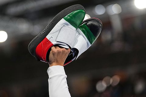 Italy's Mattia Giovanella gestures holding his shoes, after the men's curling round robin session against Britain, at the 2026 Winter Olympics, in Cortina d'Ampezzo, Italy.