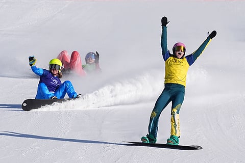 Australia's Josie Baff (17) celebrates her gold medal win past bronze medalist Italy's Michela Moioli (6) and Switzerland's Noemie Wiedmer (3) during the women's snowboard cross finals at the 2026 Winter Olympics, in Livigno, Italy.