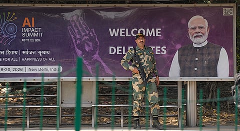 A BSF jawan stands guard at a bus stop, ahead of the AI Impact Summit 2026, in New Delhi.
