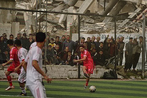 A Palestinian player of Al-Ahly Club kicks the ball during a soccer match with Gaza Sports Club at a newly constructed field surrounded by buildings destroyed in Israeli ground and air operations, in Gaza City.