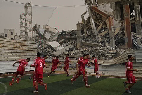Palestinian players of Al-Ahly Club warm up before a soccer match with Gaza Sports Club at a newly constructed field surrounded by buildings destroyed in Israeli ground and air operations, in Gaza City.
