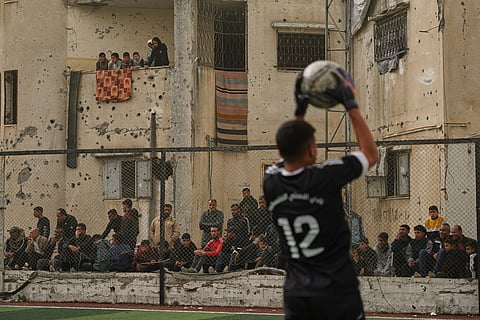 Palestinians watch a soccer match between Al-Ahly Club and Gaza Sports Club at a newly constructed field surrounded by buildings destroyed in Israeli ground and air operations, in Gaza City.
