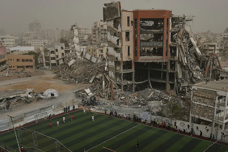 Palestinian players of Gaza Sports Club and Al-Ahly Club take part in a soccer match at a newly constructed field surrounded by buildings destroyed in Israeli ground and air operations, in Gaza City. - | Photo: AP/Jehad Alshrafi
