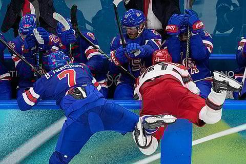 United States' Brady Tkachuk, left, challenges Denmark's Jesper Jensen Aabo during a preliminary round match of men's ice hockey between United States and Denmark at the 2026 Winter Olympics, in Milan, Italy.