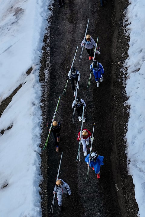 Athletes make their way to the ramp during the ski jumping women's large hill individual at the 2026 Winter Olympics, in Predazzo, Italy.