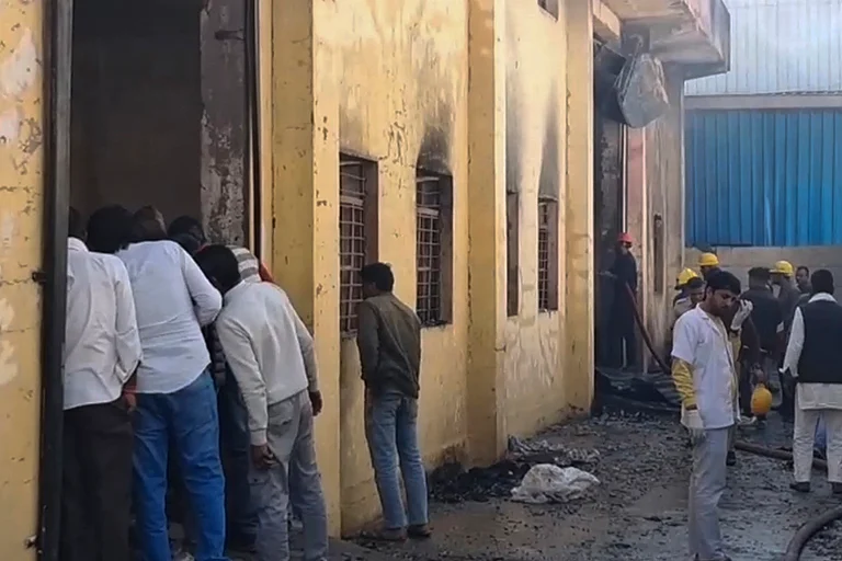 Firefighters and locals at a chemical factory building after a fire broke out at the premises, in the Khushkhera-Karouli Industrial Area of Bhiwadi, Rajasthan. Officials said seven workers were killed and two others were feared trapped after a fire broke out at the unit. - | Photo: Handout via PTI