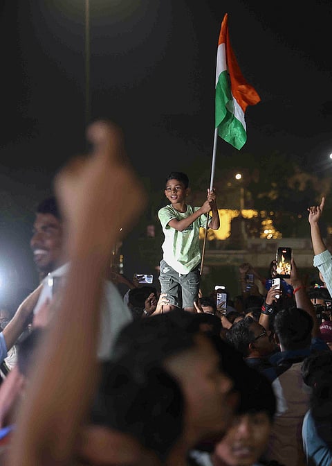 A young cricket fan waves an Indian tricolour as people celebrate India's victory over Pakistan in the ICC Men's T20 World Cup 2026 cricket match, in Mumbai.