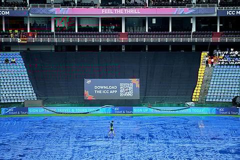 A support staff member of Ireland team walks on the covered ground as rain delayed the start of play during the T20 World Cup cricket match between Ireland and Zimbabwe in Pallekele, Sri Lanka.