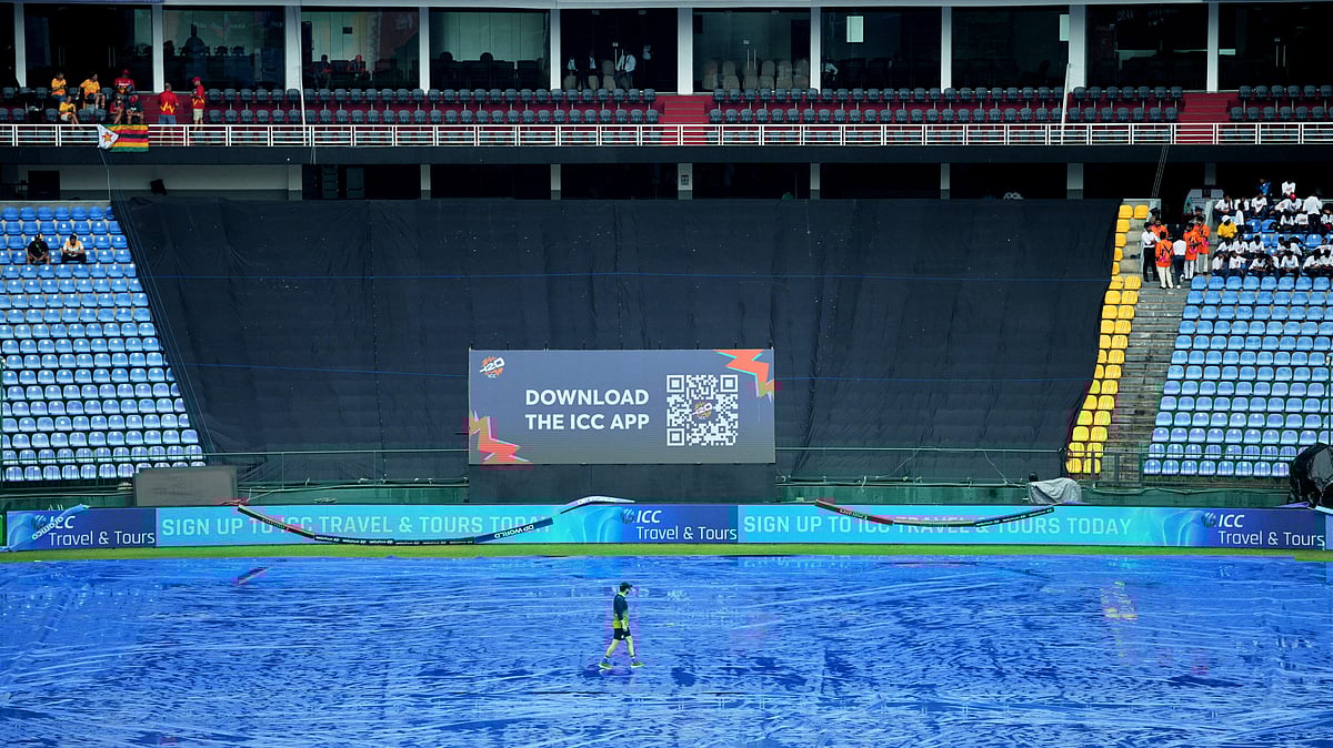 A support staff member of Ireland team walks on the covered ground as rain delayed the start of play during the T20 World Cup cricket match between Ireland and Zimbabwe in Pallekele, Sri Lanka, Tuesday, Feb. 17, 202 - (AP Photo/Eranga Jayawardena)