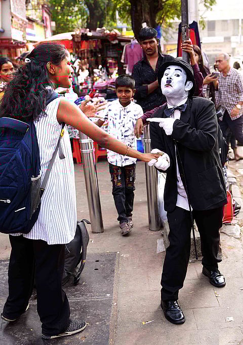 Dressed as Charlie Chaplin, Afsar Khan greets a passerby with a warm handshake in the busy streets of Dadar, sharing a moment of joy amid the rush of Mumbai.