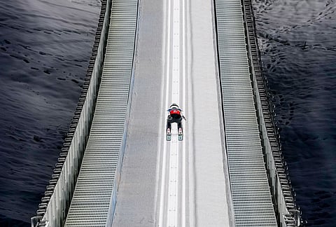 Song Qiwu, of China, goes down the ramp during his trial jump of the ski jumping men's super team competition at the 2026 Winter Olympics, in Predazzo, Italy.