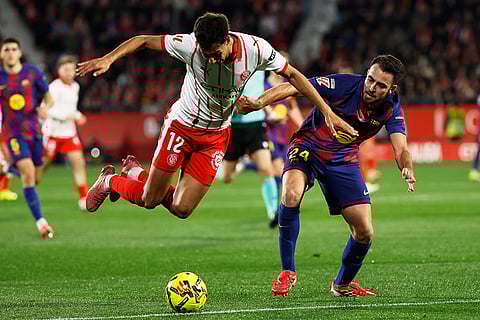 Girona's Vitor Reis is tacked by Barcelona's Eric Garcia during a Spanish La Liga soccer match between Girona and Barcelona in Girona, Spain.