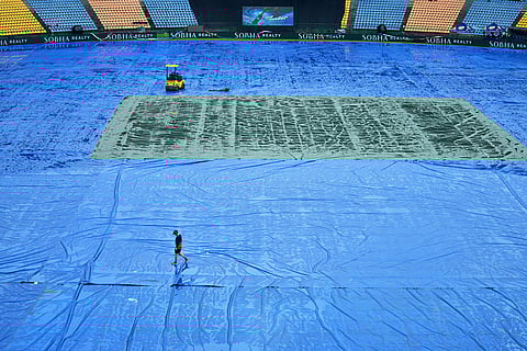 A support staff member of Ireland team walks on the covered ground as rain delayed the start of play during the T20 World Cup cricket match between Ireland and Zimbabwe in Pallekele, Sri Lanka.