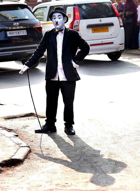 Dressed as Charlie Chaplin, Afsar Khan greets a passerby with a warm handshake in the busy streets of Dadar, sharing a moment of joy amid the rush of Mumbai.