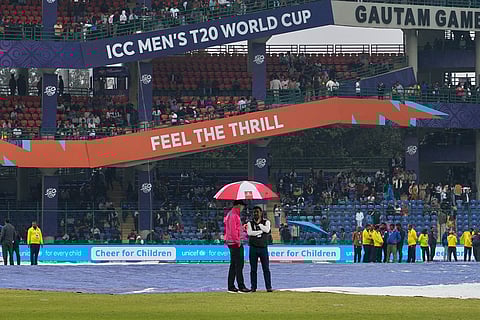 Ground staffs stand on the ground for a rain during the break of the T20 World Cup cricket match between South Africa and United Arab Emirates in New Delhi, India.