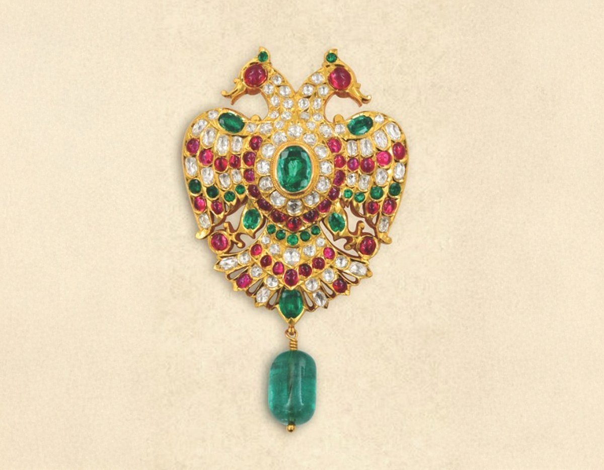 Ornate gold crown brooch with colorful gemstones and blue bead drop