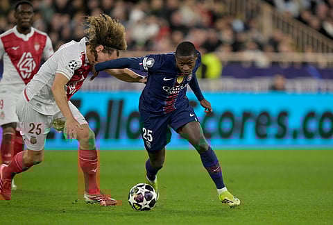 PSG's Nuno Mendes, center, and Monaco's Wout Faes challenge for the ball during the first-leg of the Champions League playoff soccer match between Monaco and Paris Saint-Germain in Monaco.