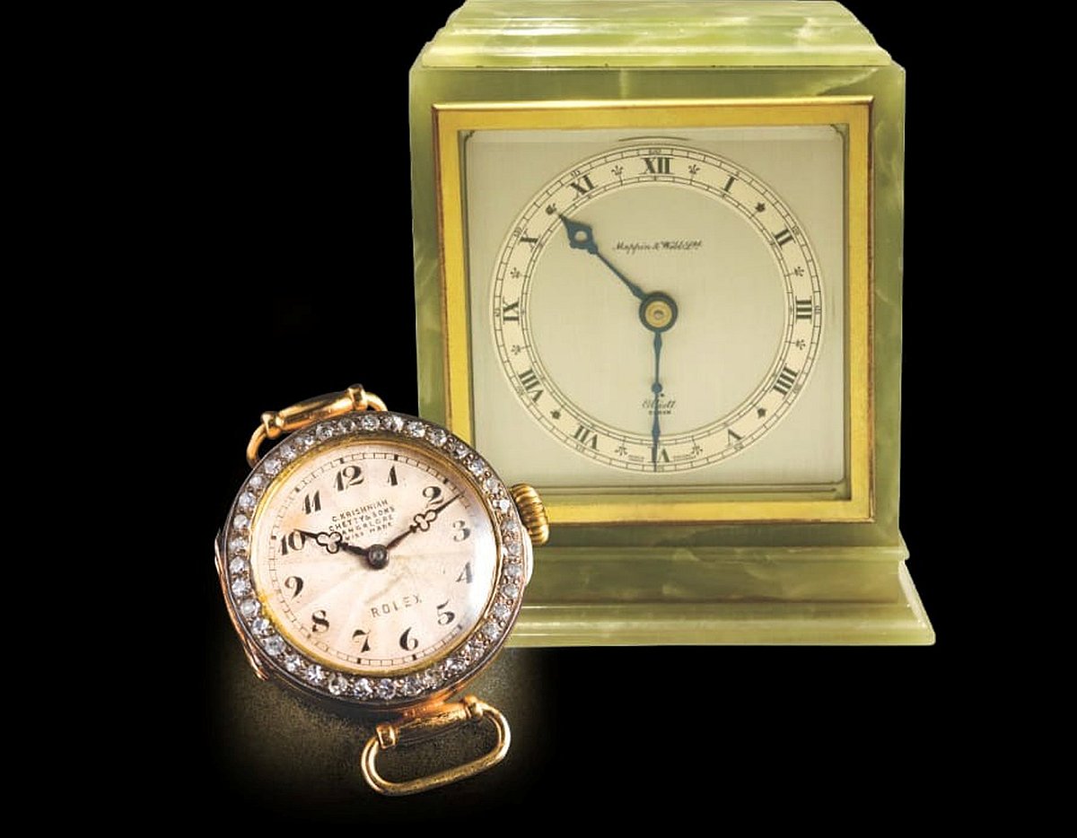 Vintage pocket watch and brass carriage clock on dark background
