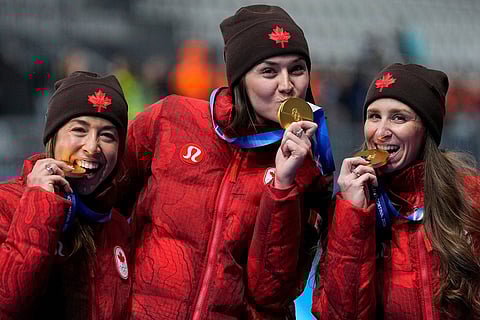 Team Canada with Isabelle Weidemann, center, Valerie Maltais, left, and Ivanie BLondin, right, celebrate winning the gold medal in the final of the women's team pursuit speedskating race at the 2026 Winter Olympics, in Milan, Italy.