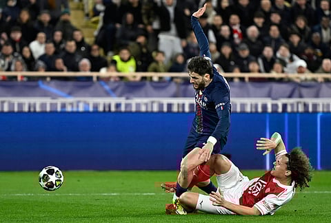 PSG's Khvicha Kvaratskhelia, left, and Monaco's Wout Faes challenge for the ball during the first-leg of the Champions League playoff soccer match between Monaco and Paris Saint-Germain in Monaco.