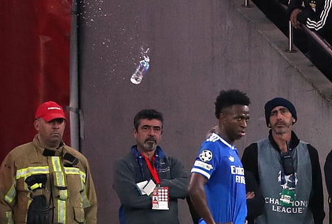 A plastic bottle filled with water is thrown from the stands toward Real Madrid's Vinícius Júnior during a Champions League playoff soccer match between Benfica and Real Madrid in Lisbon, Portugal.