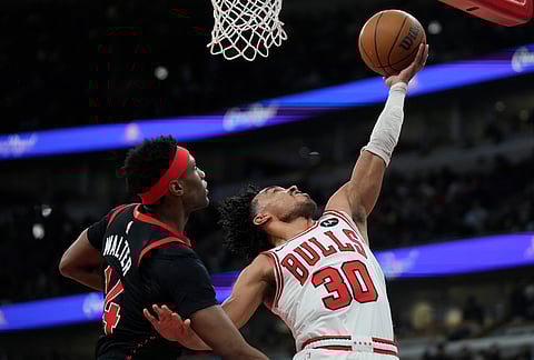 Chicago Bulls guard Tre Jones (30) shoots as Toronto Raptors guard Ja'kobe Walter, left, defends during the first half of an NBA basketball game in Chicago.