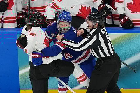 Linesperson Kristyna Hajkova (16) tries to separate United States' Megan Keller (5) and Canada's Laura Stacey (7) during the third period of the women's ice hockey gold medal game at the 2026 Winter Olympics, in Milan, Italy, Thursday, Feb. 19, 2026.