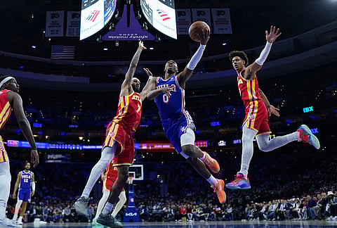 Philadelphia 76ers' Tyrese Maxey (0) goes up to shoot against Atlanta Hawks' Nickeil Alexander-Walker (7) and Jalen Johnson, right, during the first half of an NBA basketball game in Philadelphia.