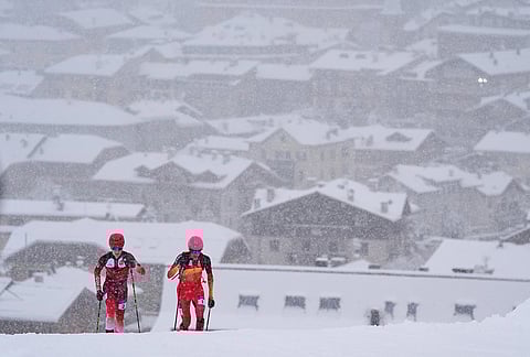 Spain's Oriol Cardona Coll, right, competes alongside Switzerland's Jon Kistler backdropped by a snow covered Bormio village, during a ski mountaineering men's sprint semifinal, at the 2026 Winter Olympics, in Bormio, Italy.