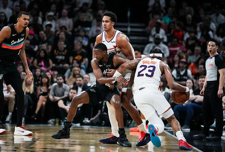 Phoenix Suns guard Jordan Goodwin (23) drives past defense from San Antonio Spurs forward Harrison Barnes (40) as Barnes is held up by Phoenix Suns forward Ryan Dunn (0) in the second quarter of an NBA basketball game in Austin, Texas. - | Photo: Sara Diggins/Austin American-Statesman via AP