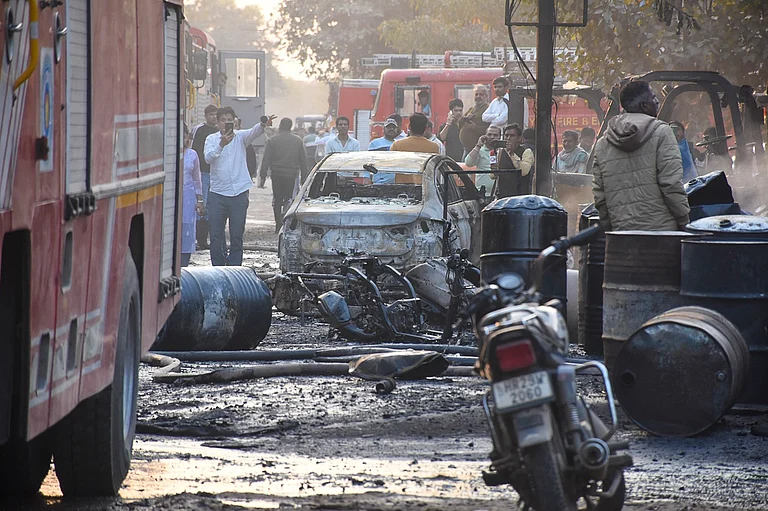 People gather around charred remains after a fire broke out at a factory in Sector 24, in Faridabad, Monday, Feb. 16, 2026. More than 35 people were rushed to hospitals with burns in the incident. - PTI